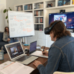 Homme avec casque VR prenant des notes devant plusieurs écrans.