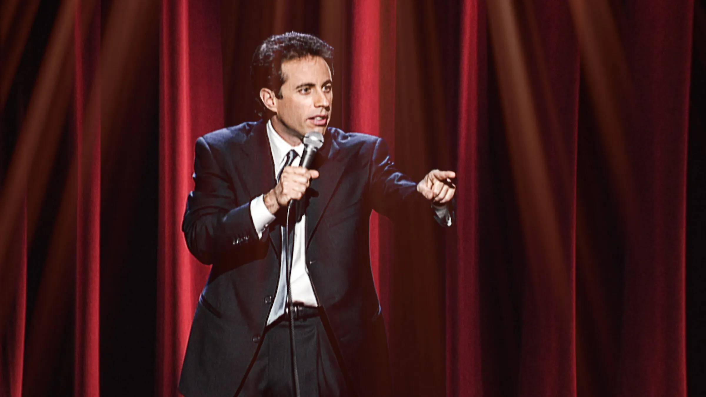 Jerry Seinfeld performing stand-up comedy on stage during a live show