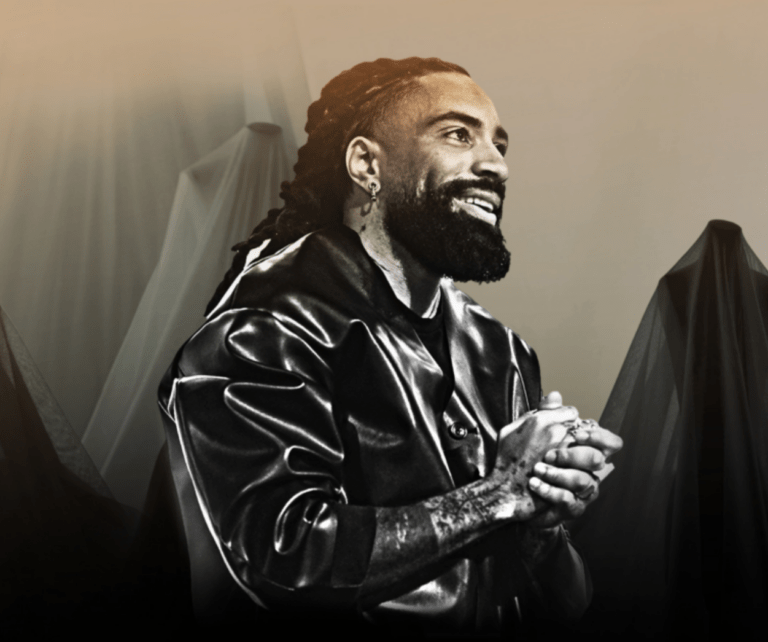 Fary sur scène lors d’un spectacle de stand-up à Paris, costume élégant et mise en scène minimaliste.